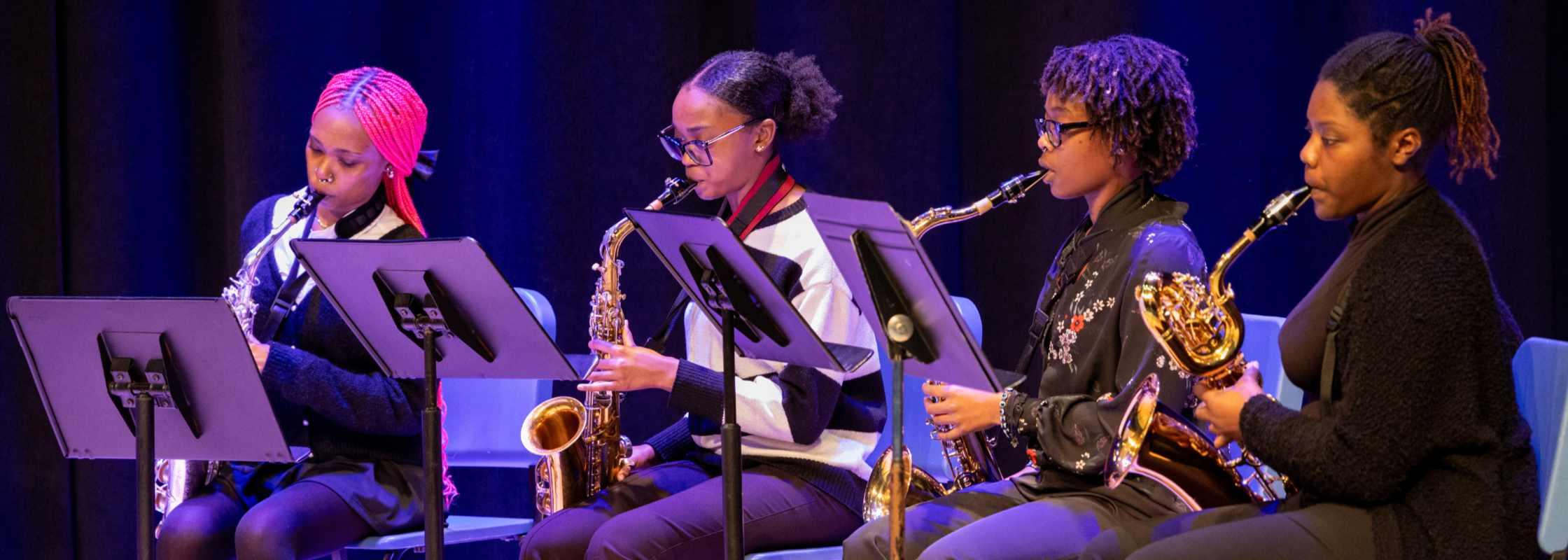 four students playing woodwind instruments
